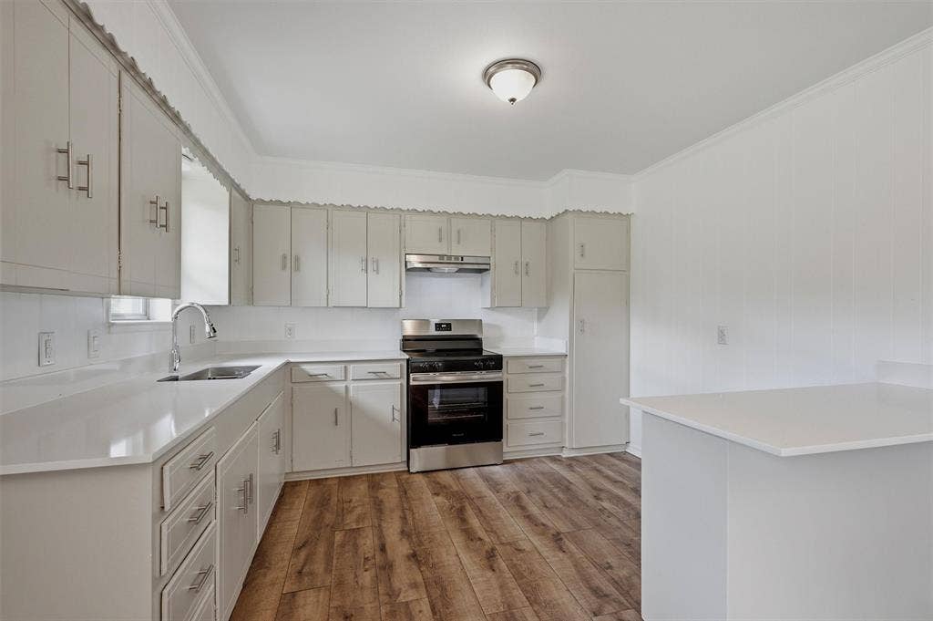 607 N Louisiana Drive, Celina, TX 75009 Kitchen featuring light-toned cabinetry, quartz countertops, stainless steel gas range, wood-finish flooring, and a flush-mount ceiling light fixture