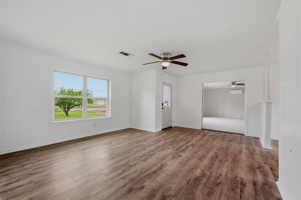 607 N Louisiana Drive, Celina, TX 75009 Open-concept interior featuring wood-finish flooring, a ceiling fan, and large windows with natural light