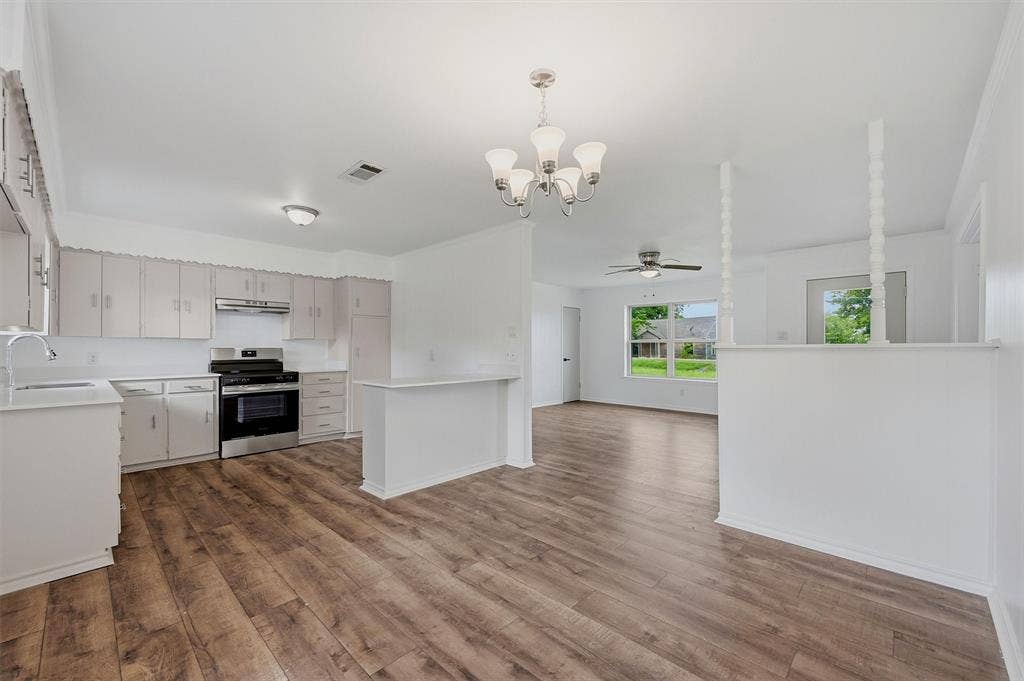 607 N Louisiana Drive, Celina, TX 75009 Kitchen featuring wood-finish flooring, white cabinetry, a stainless steel range, a peninsula, and a multi-light chandelier