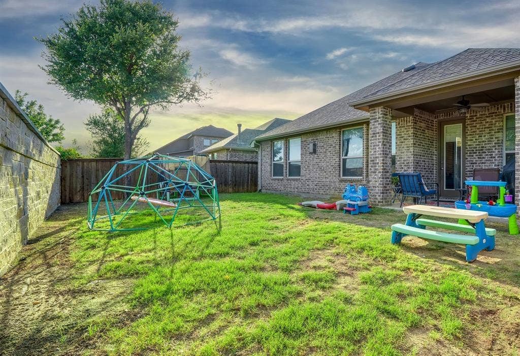 124 Village Creek Drive, McKinney, TX 75071 Backyard featuring a covered patio, brick exterior wall, masonry perimeter fencing, and mature trees