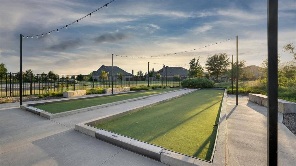 124 Village Creek Drive, McKinney, TX 75071 Dual bocce ball courts featuring synthetic turf, concrete borders, stone block seating, and overhead string lighting