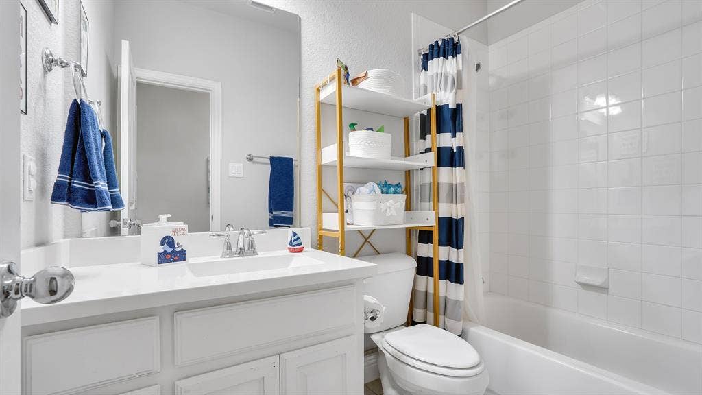 124 Village Creek Drive, McKinney, TX 75071 Bathroom featuring a white vanity with an integrated sink, polished chrome faucet, full-width mirror, and a tile-surround tub