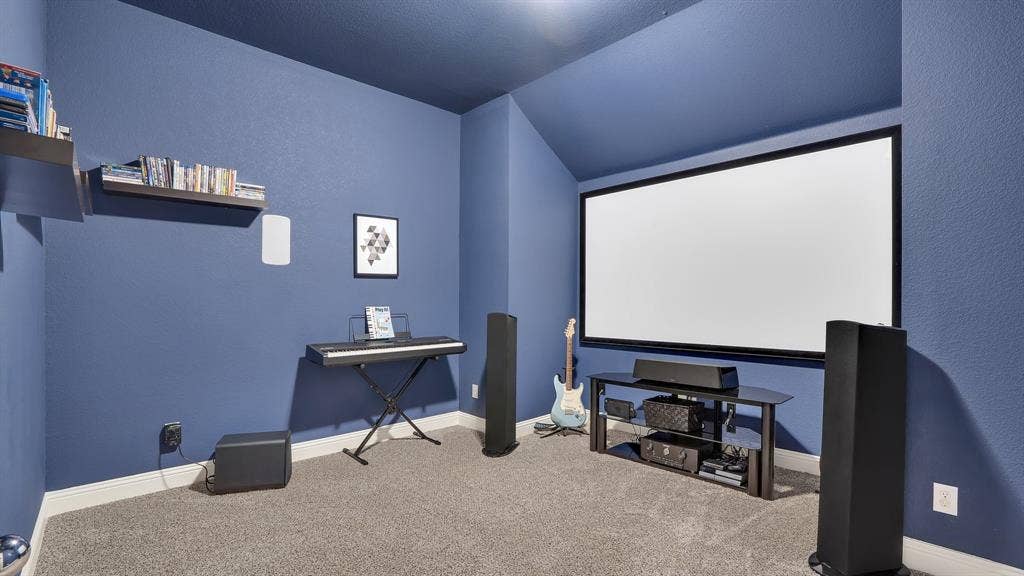 124 Village Creek Drive, McKinney, TX 75071 Dedicated media room featuring a wall-mounted projector screen, vaulted ceilings, and wall-mounted shelving