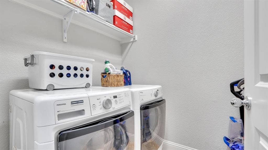 124 Village Creek Drive, McKinney, TX 75071 Laundry area featuring white appliances and wall-mounted wire shelving