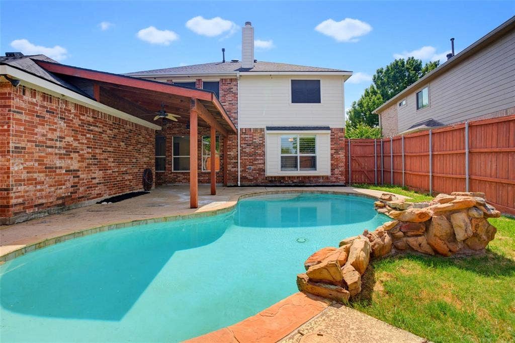 1402 Bradford Trace Drive, Allen, TX 75002 Backyard featuring an in-ground swimming pool with a stone water feature, a covered patio with wooden structural supports, brick and siding exterior, and a wood privacy fence