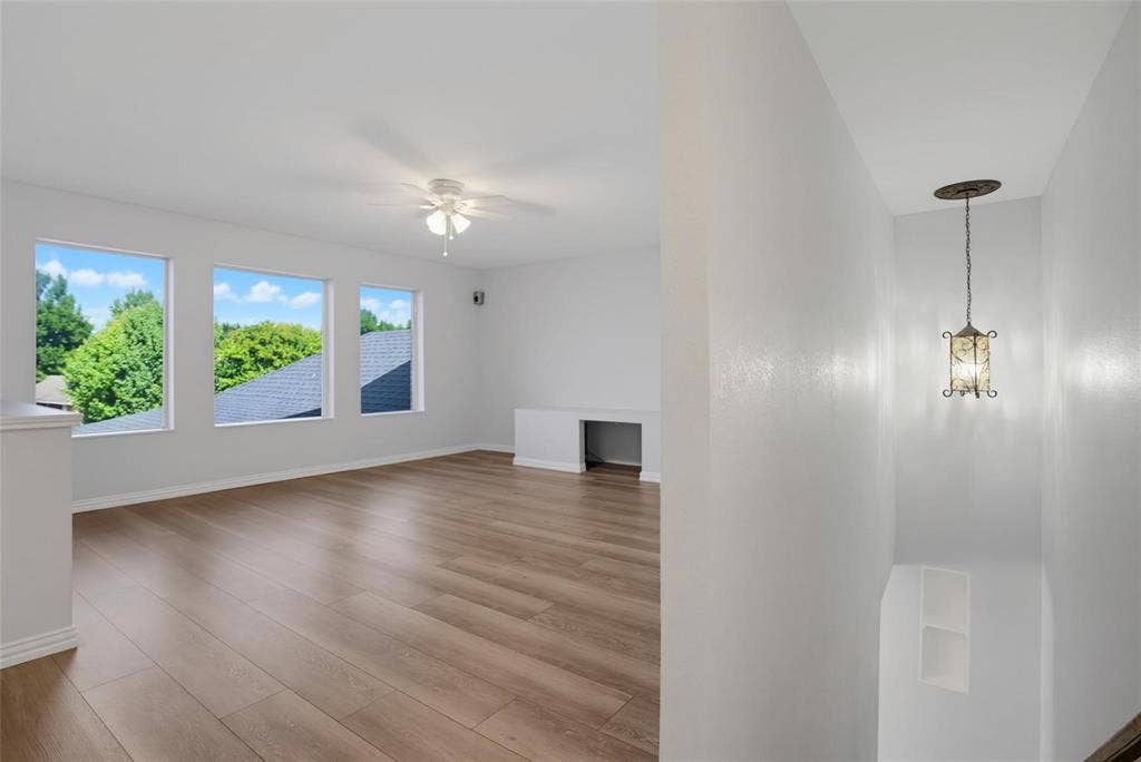1402 Bradford Trace Drive, Allen, TX 75002 Open interior space featuring wood-finish flooring, multiple windows, a ceiling fan, a built-in desk, and a pendant light fixture