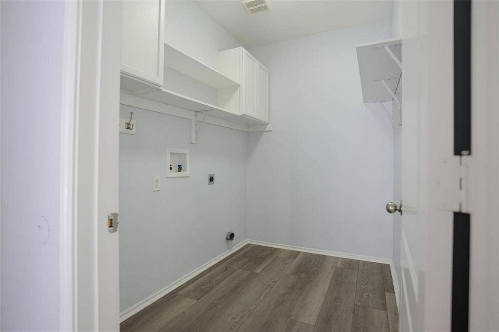 1402 Bradford Trace Drive, Allen, TX 75002 Utility room featuring wood-finish flooring, white shaker-style cabinetry, open wall shelving, and dedicated hookups for laundry appliances