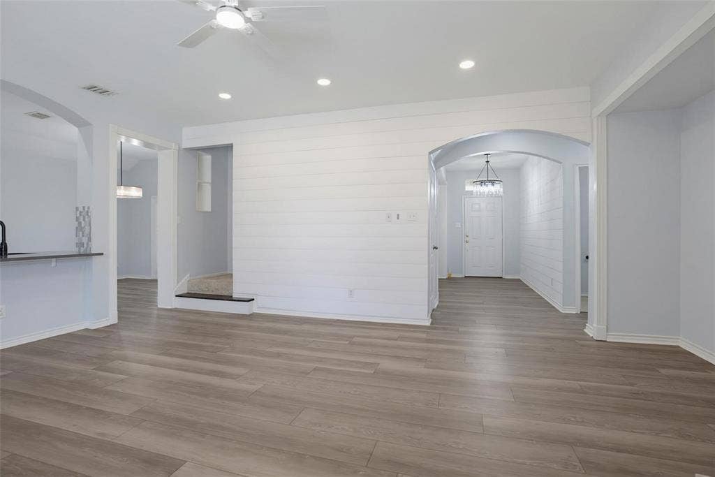 1402 Bradford Trace Drive, Allen, TX 75002 Open interior featuring wood-finish flooring, white shiplap accent wall, arched doorways, recessed lighting, and a ceiling fan with integrated light fixture