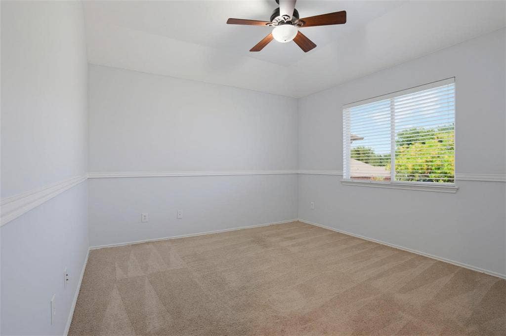 1402 Bradford Trace Drive, Allen, TX 75002 Room interior featuring neutral carpeting, a tray ceiling, ceiling fan with integrated lighting, chair rail molding, and window with blinds