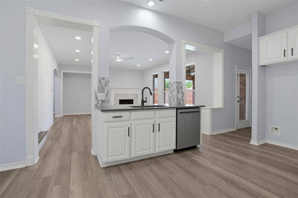 1402 Bradford Trace Drive, Allen, TX 75002 Kitchen island featuring a stone-surface countertop, under-mount sink with a matte black pull-down faucet, white shaker-style cabinetry, stainless steel dishwasher, and mosaic tile backsplash