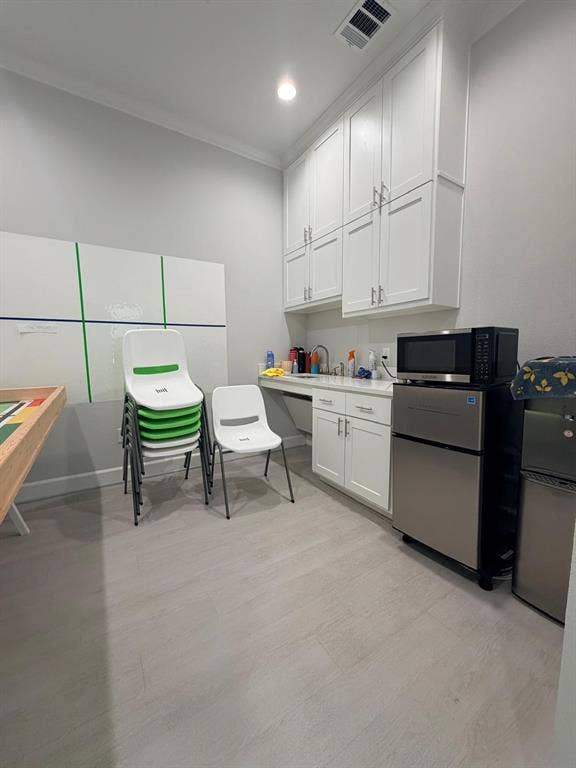 2120 Prairie Drive, #601, Prosper, TX 75078 Floor-to-ceiling white cabinetry, wood-finish flooring, integrated sink with stone countertop, and crisp neutral wall finish
