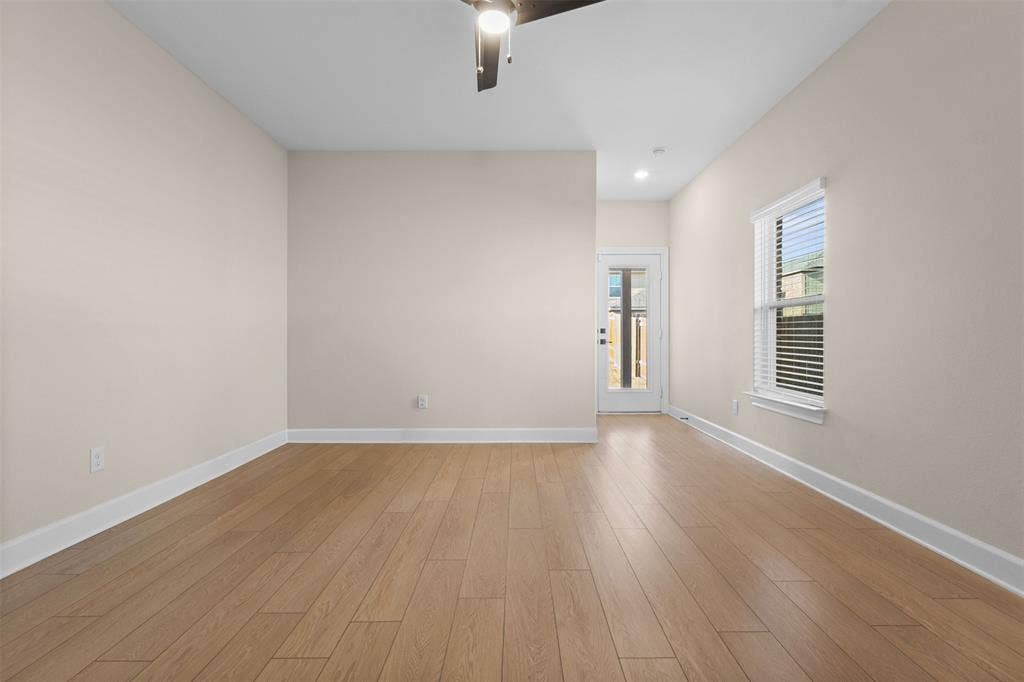 Room with neutral wall finish, wood-finish flooring, ceiling fan with integrated lighting, window with horizontal blinds, and a door featuring glass paneling