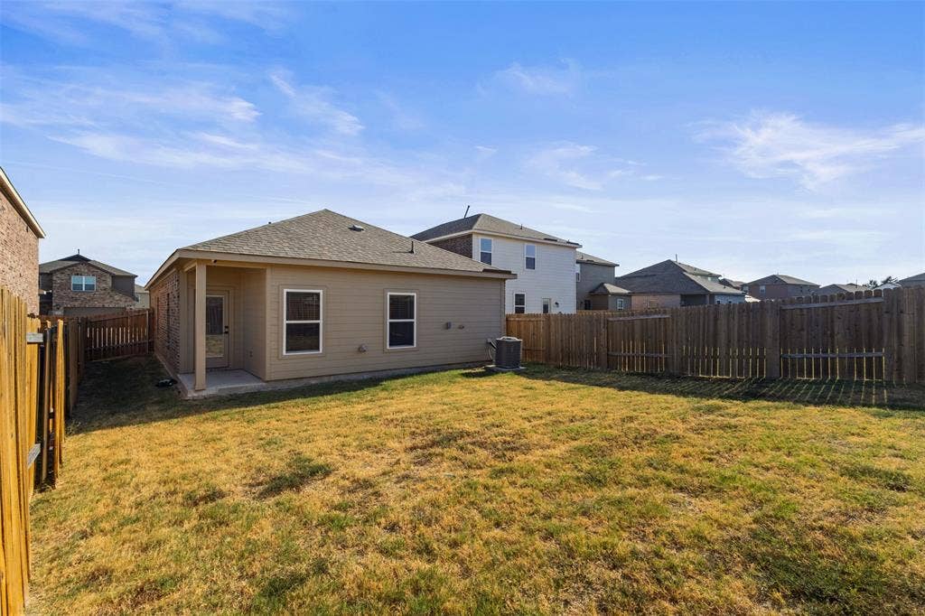 Rear exterior featuring a covered patio, tan siding, and a fenced backyard