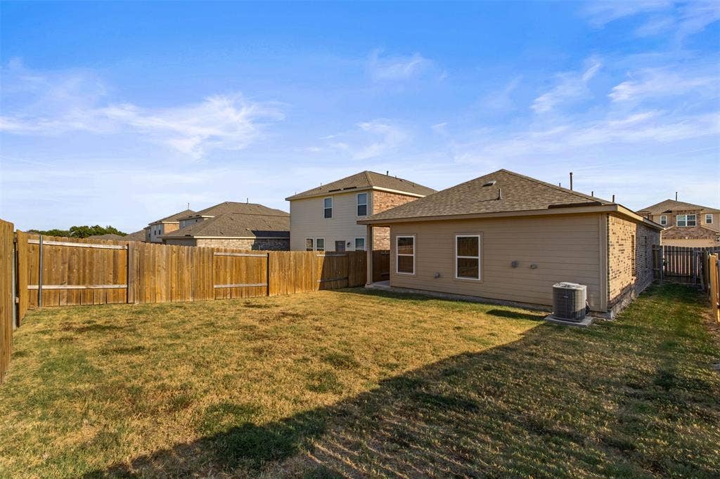 Backyard featuring a grass lawn, perimeter wood fencing, and composite siding exterior