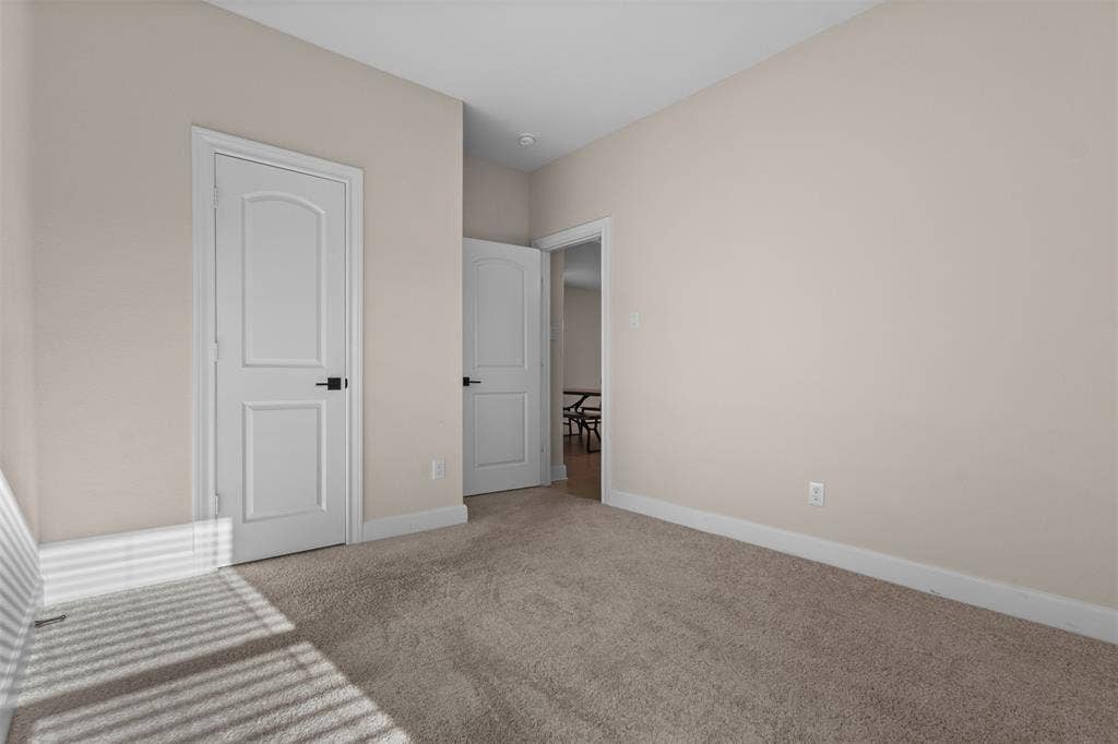 Interior space featuring neutral wall tones, wall-to-wall carpeting, two-panel interior doors, and matte black hardware