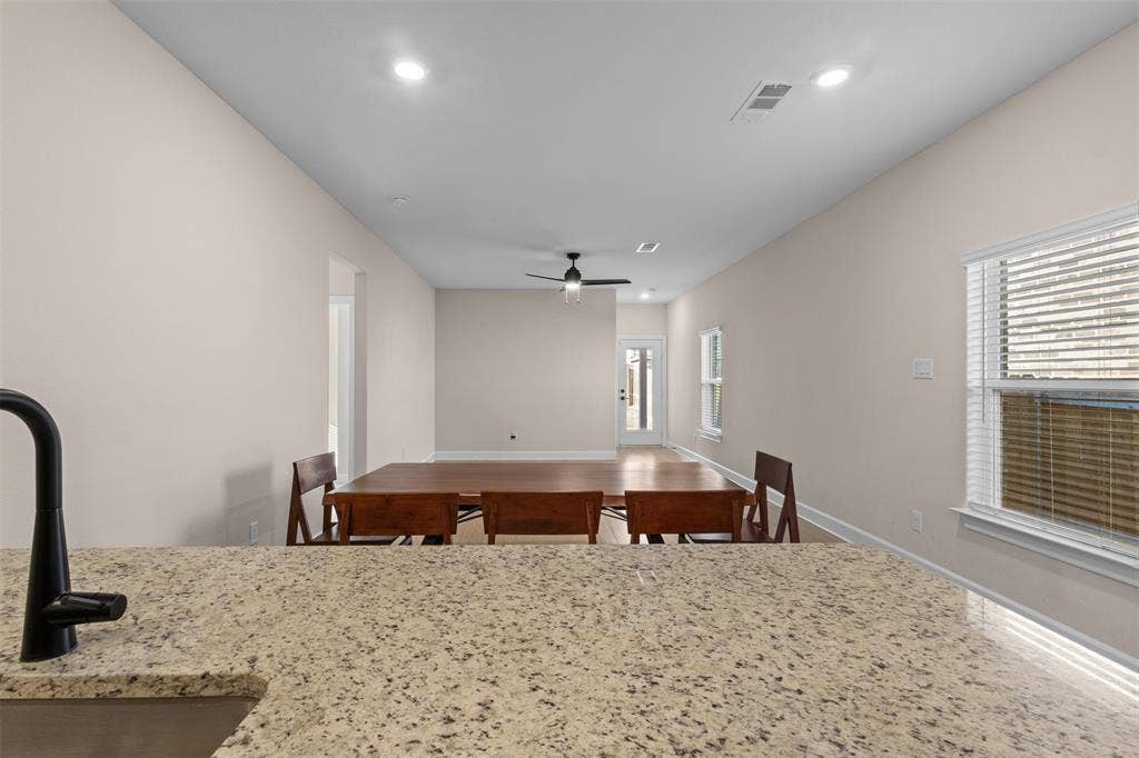 Speckled stone countertop with a matte black faucet, recessed lighting, and ceiling fan fixture