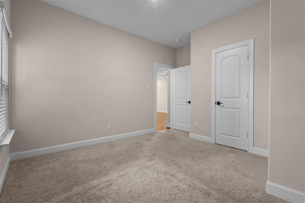 Neutral wall color, carpeted flooring, white two-panel interior doors, and matte black door hardware