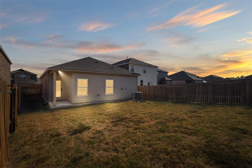 Rear exterior featuring neutral-toned siding, a covered patio area, and a privacy wood fence