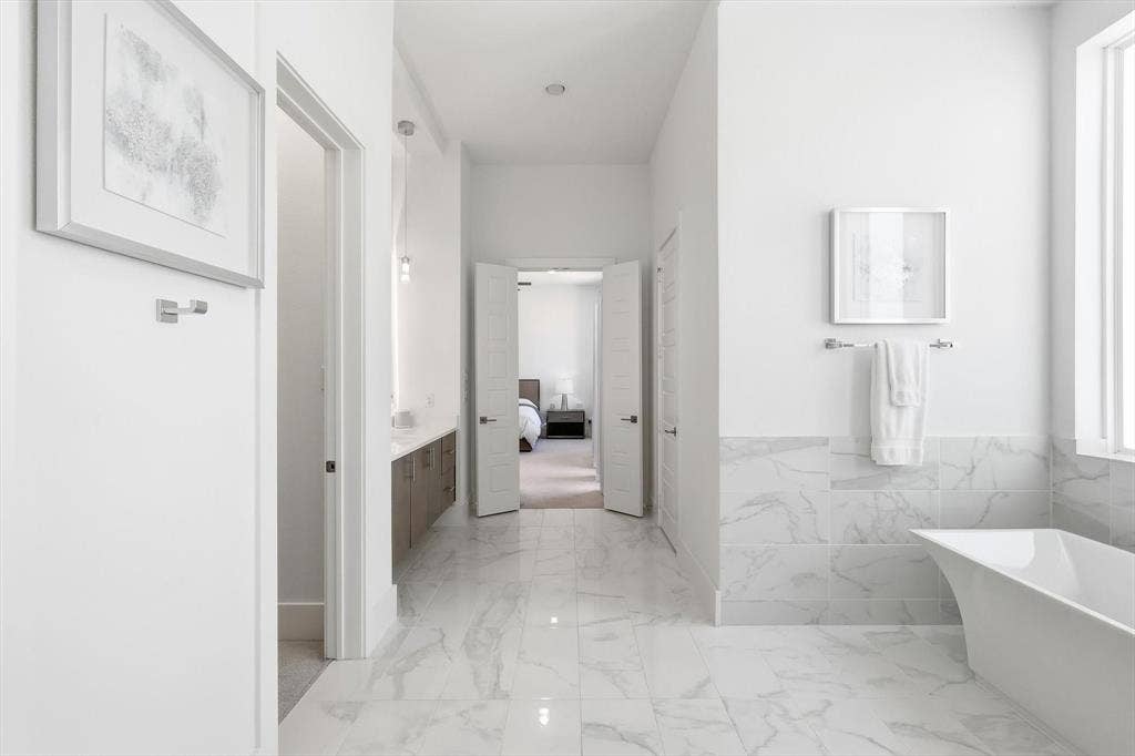 7853 Element Avenue, Plano, TX 75024 Freestanding soaking tub featuring a stone-look tiled surround, light-toned stone flooring, wall-mounted hardware, and double-door entry