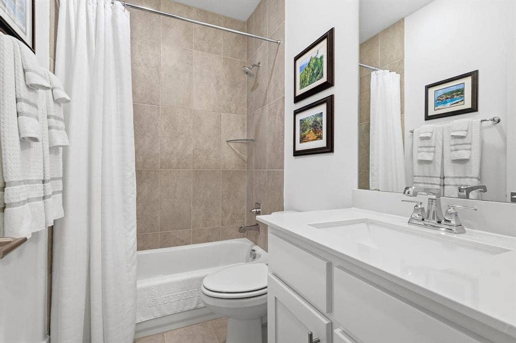 7853 Element Avenue, Plano, TX 75024 Bathroom featuring a white vanity cabinet with a solid surface countertop, an undermount sink with a polished chrome faucet, a tub-shower combination with floor-to-ceiling tile surround, and a full-width wall mirror