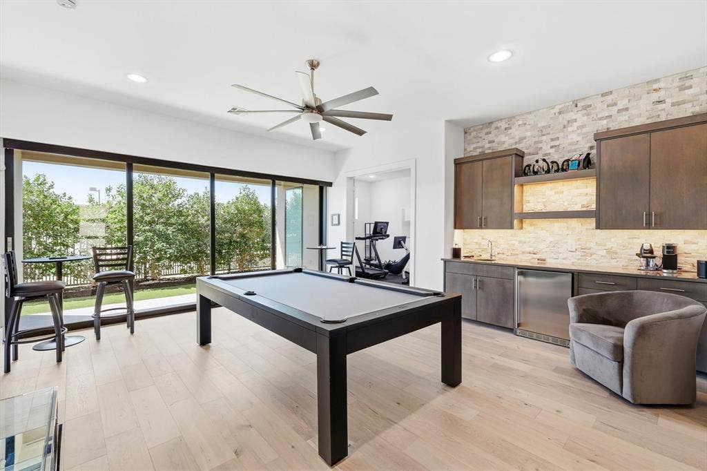 7853 Element Avenue, Plano, TX 75024 Multi-panel sliding glass doors, wet bar with wood cabinetry and stone backsplash, recessed lighting, and wood-finish flooring