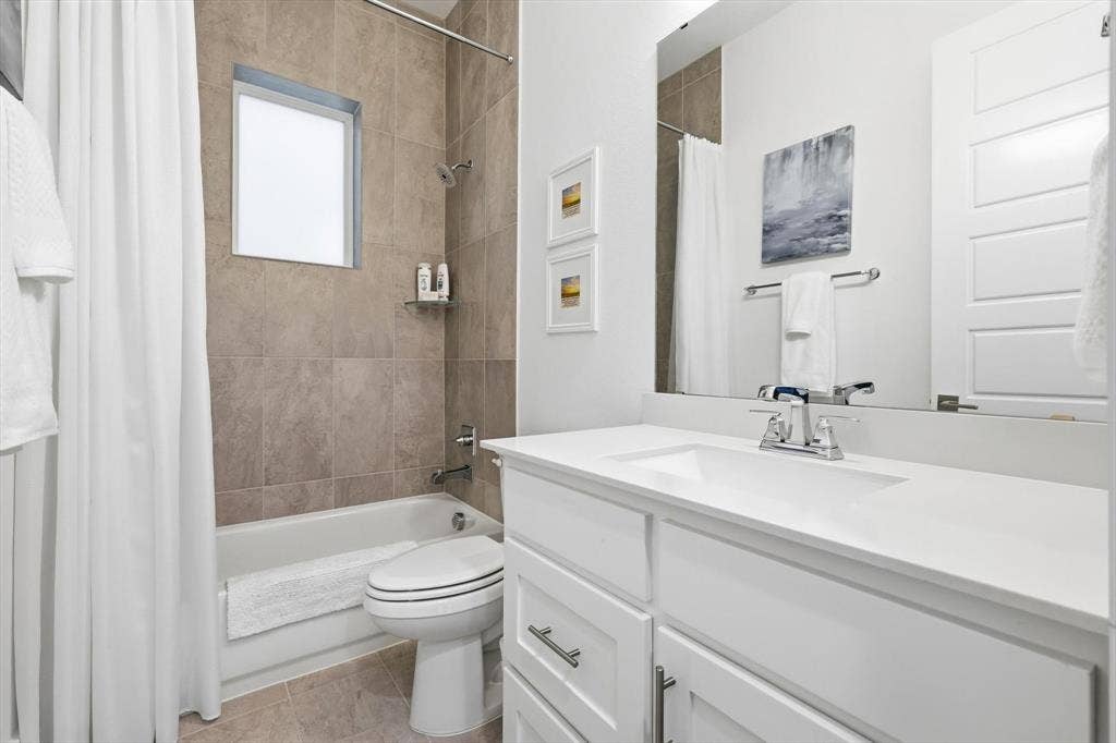 7853 Element Avenue, Plano, TX 75024 Bathroom featuring a white vanity cabinet with a solid surface countertop, rectangular under-mount sink, chrome hardware, large vanity mirror, and a tub-shower combination with floor-to-ceiling tile surround