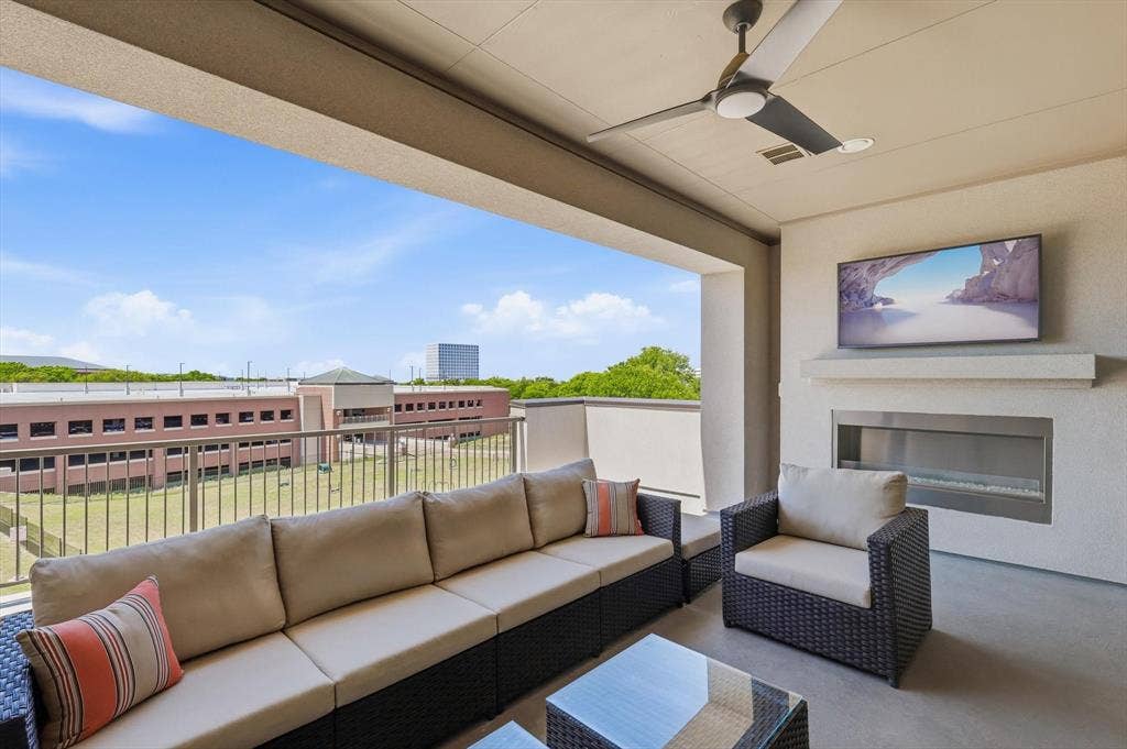 7853 Element Avenue, Plano, TX 75024 Covered balcony featuring a sleek, horizontal gas fireplace, mounted television, ceiling fan, and metal railing