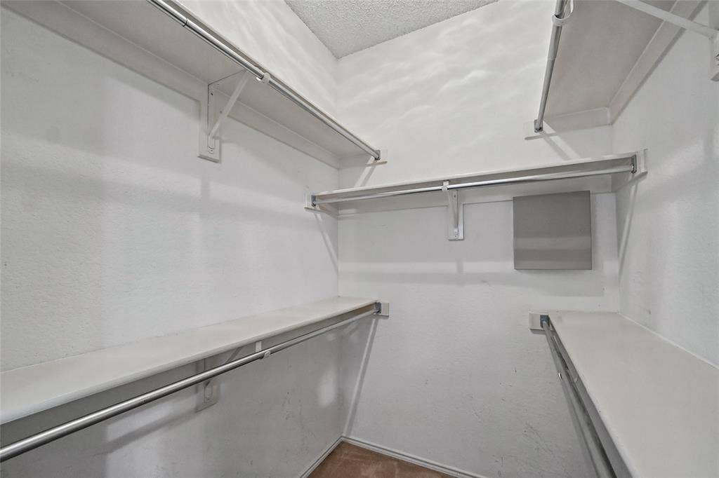 714 Cottonwood Bend Drive, Allen, TX 75002 Walk-in closet featuring multi-level shelving, integrated metal hanging rods, and neutral interior finishes