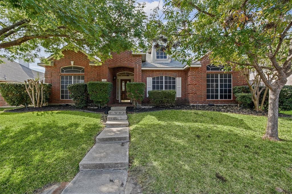 714 Cottonwood Bend Drive, Allen, TX 75002 Brick exterior featuring arched window detailing, a recessed covered entryway, and multi-pane windows