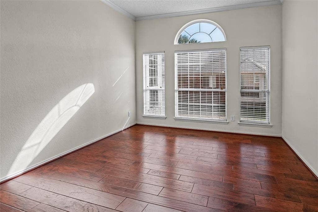 714 Cottonwood Bend Drive, Allen, TX 75002 Wood-finish flooring, high ceilings with crown molding, and an arched transom window above a triple-window configuration with integrated blinds