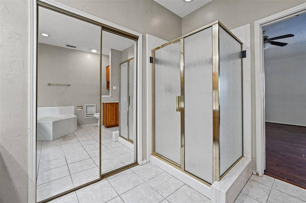 714 Cottonwood Bend Drive, Allen, TX 75002 Bathroom featuring a glass-enclosed shower, mirrored sliding closet doors, built-in soaking tub, tiled flooring, and recessed lighting