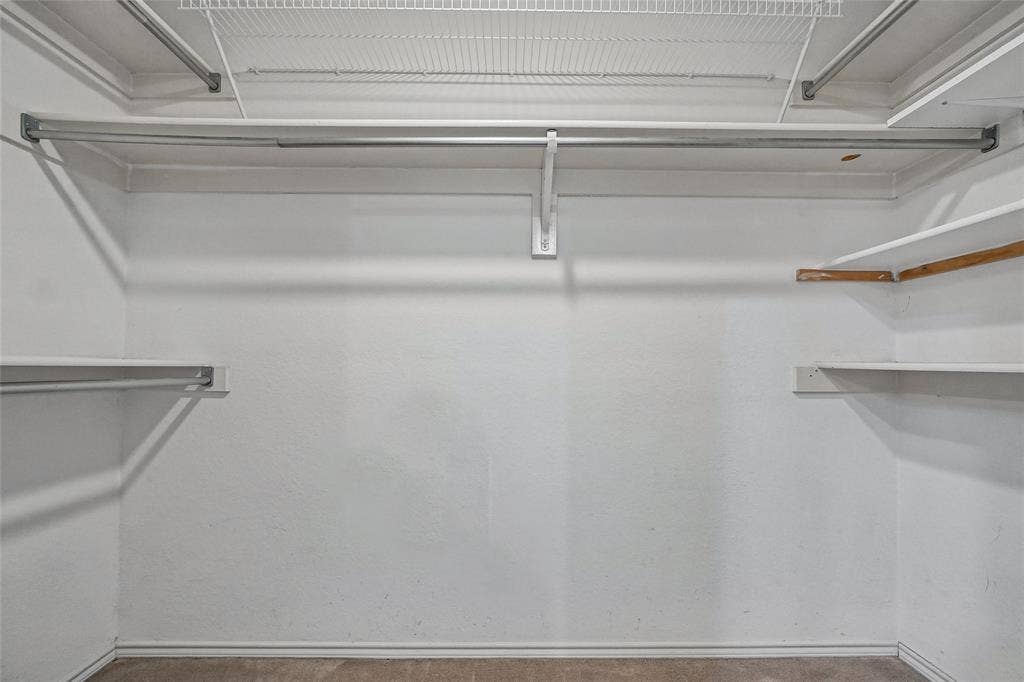 714 Cottonwood Bend Drive, Allen, TX 75002 Walk-in closet featuring multi-level metal hanging rods and white fixed shelving
