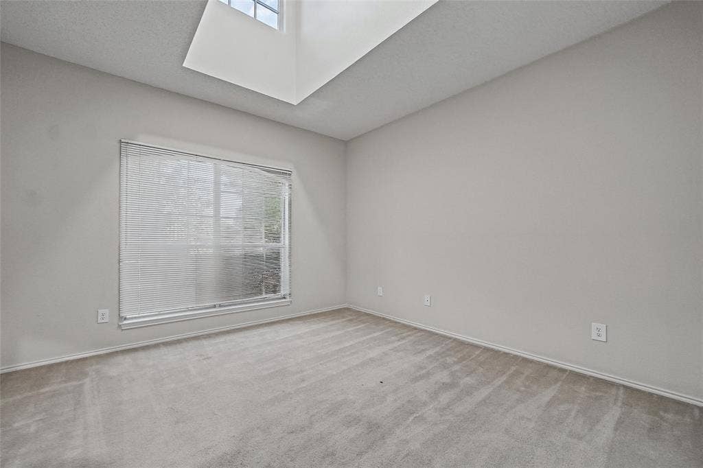 714 Cottonwood Bend Drive, Allen, TX 75002 Neutral-toned interior space featuring a recessed skylight, wall-to-wall carpeting, and a large window with fitted blinds