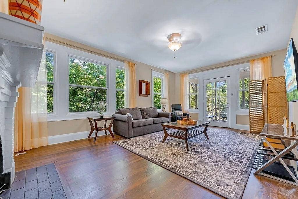 Living area featuring wood-finish flooring, a masonry fireplace, abundant windows, and a glass-paneled exterior door