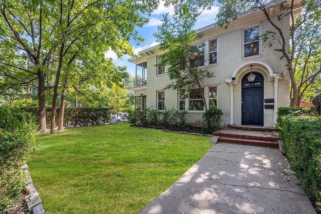 Two-story painted brick exterior featuring an arched entryway, decorative molding, multi-pane windows, and a screened porch