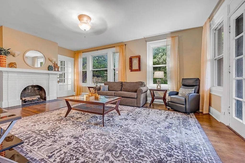Living area featuring a white fireplace mantle, wood-finish flooring, multi-pane windows, and a glass-paned door