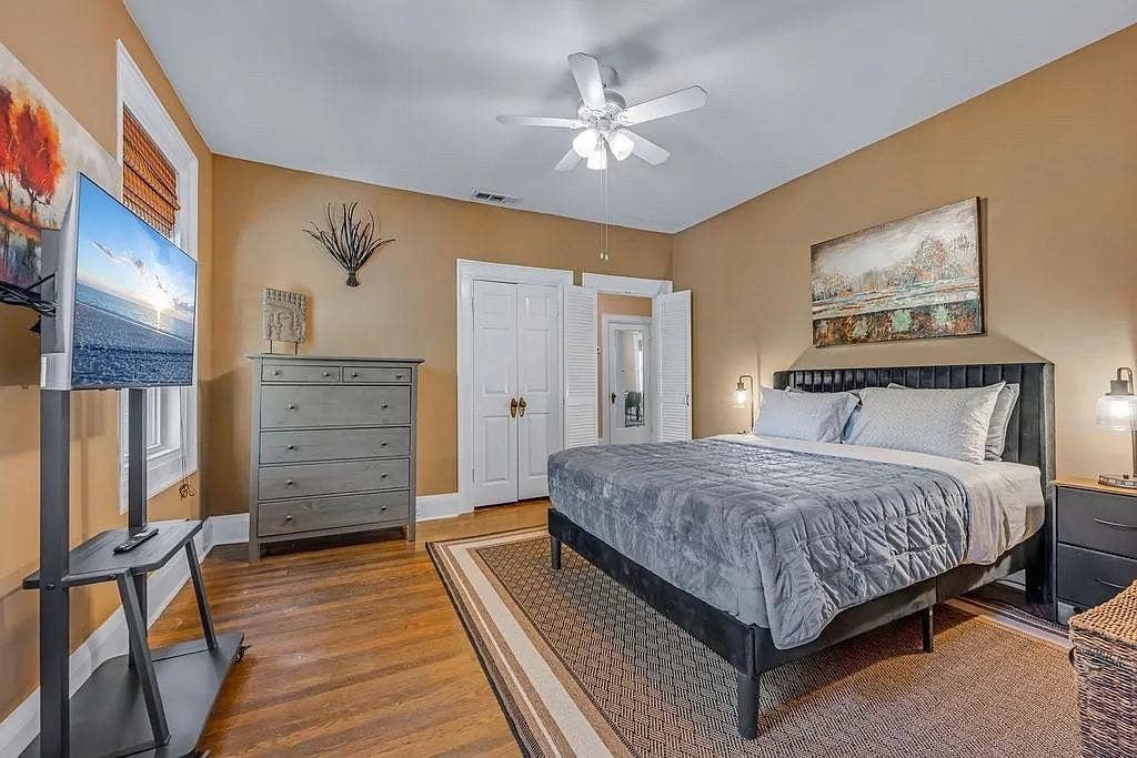 Wood-finish flooring, white paneled double-door closet, and ceiling-mounted fan with integrated lighting