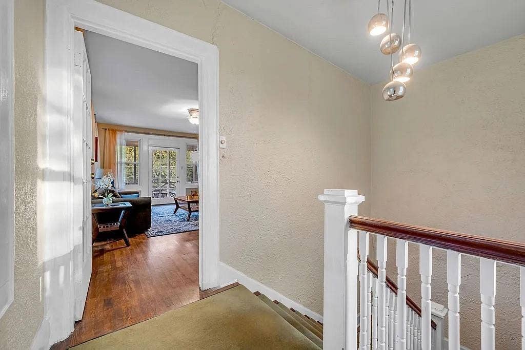 Staircase featuring a white wooden balustrade with a dark wood handrail, polished multi-globe pendant lighting, and wood-finish flooring
