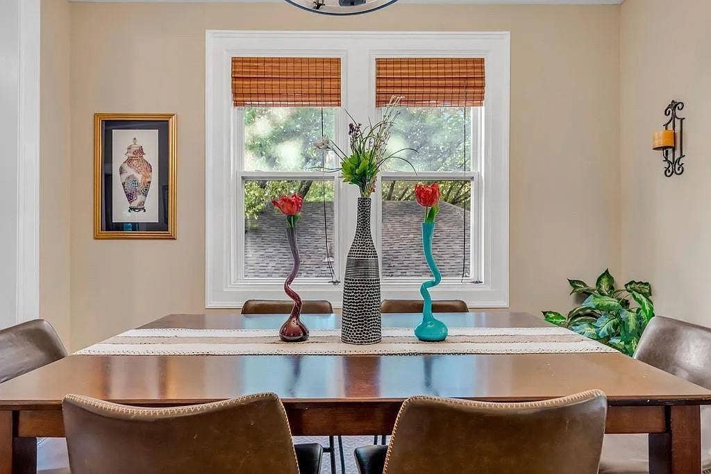 Double-hung window with white millwork casing, woven wood shades, and a decorative wall-mounted metal sconce