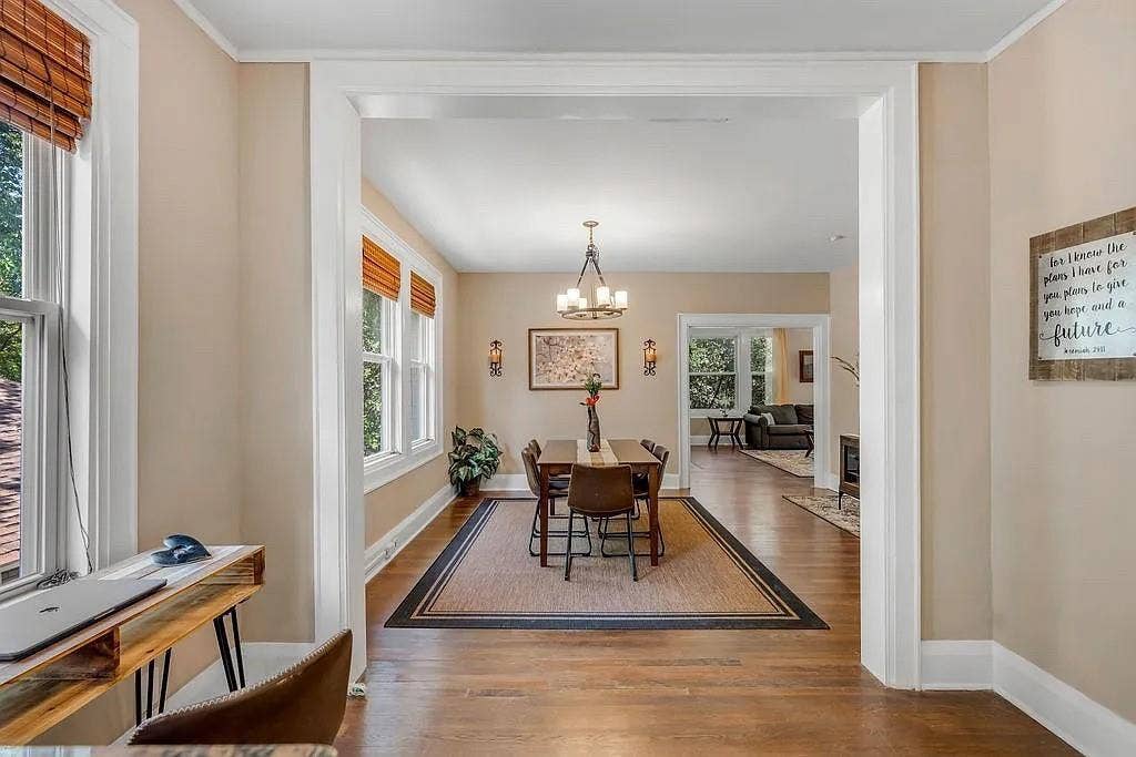 Hardwood flooring, multi-pane windows with integrated casings, crown molding, and polished nickel multi-arm chandelier lighting