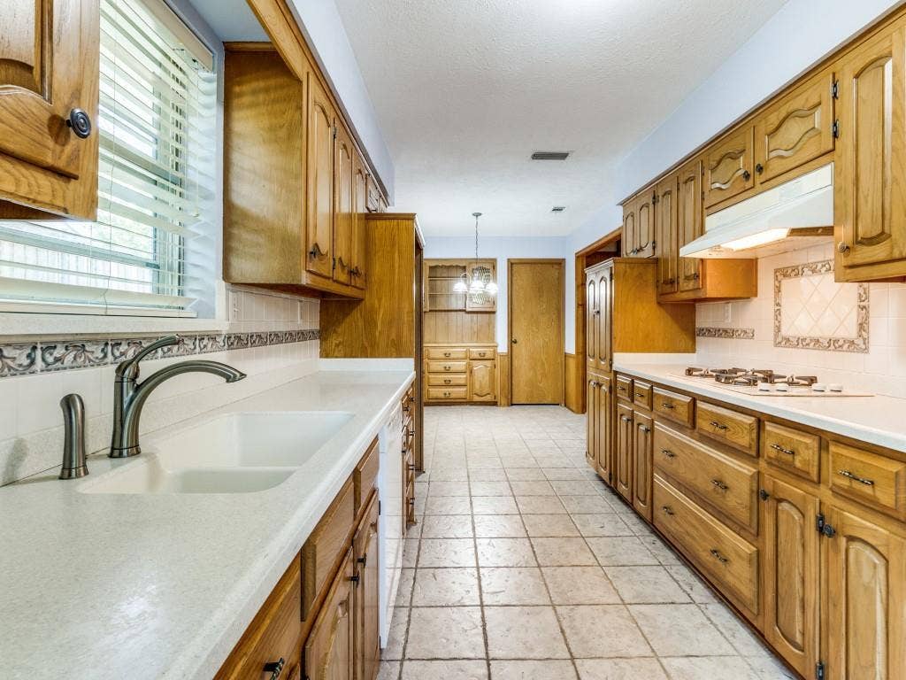 2007 Mistletoe Drive, Richardson, TX 75081 Kitchen featuring a sink, under cabinet range hood, decorative backsplash, white appliances, and light countertops