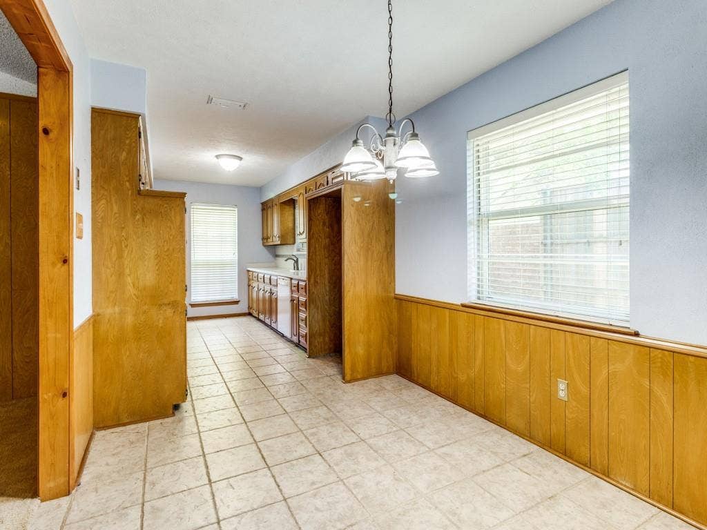 2007 Mistletoe Drive, Richardson, TX 75081 Kitchen featuring brown cabinets, a chandelier, a wainscoted wall, dishwasher, and wooden walls