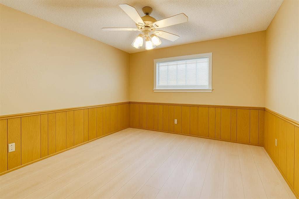 2007 Mistletoe Drive, Richardson, TX 75081 Unfurnished bedroom featuring a wainscoted wall, wood finished floors, and ceiling fan