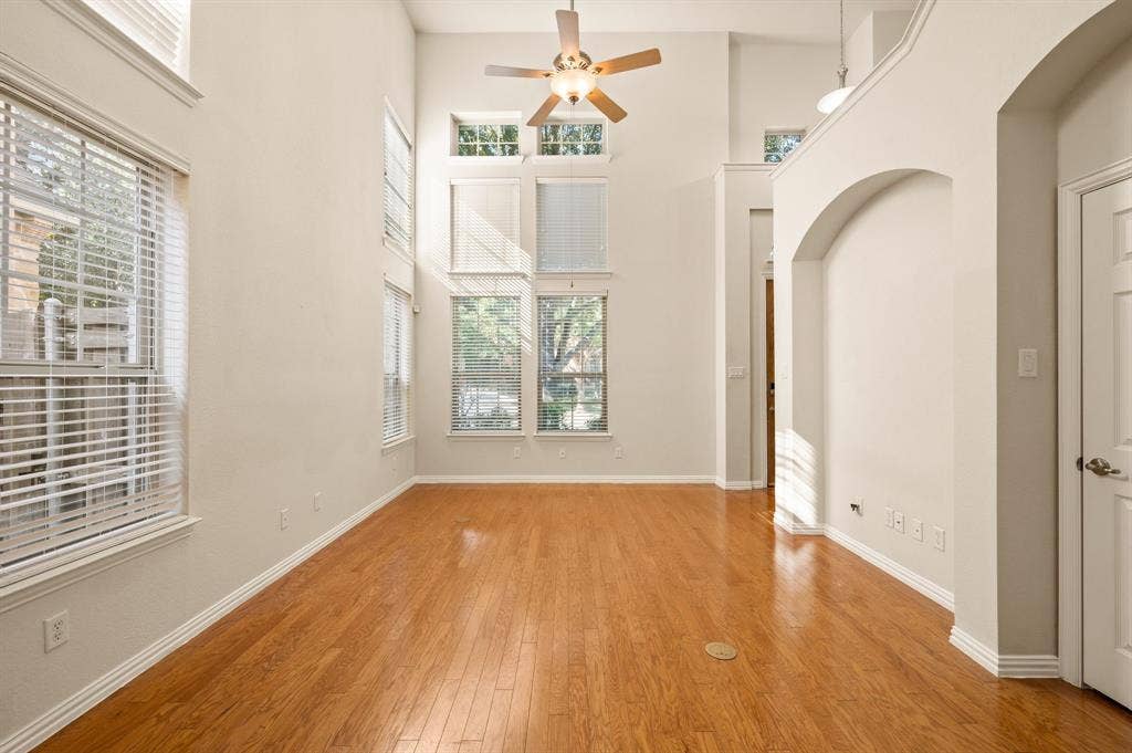 1712 Coronado Street, Allen, TX 75013 High-ceiling interior featuring wood-finish flooring, multi-level windows, architectural arched alcove, and a central ceiling fan with integrated lighting