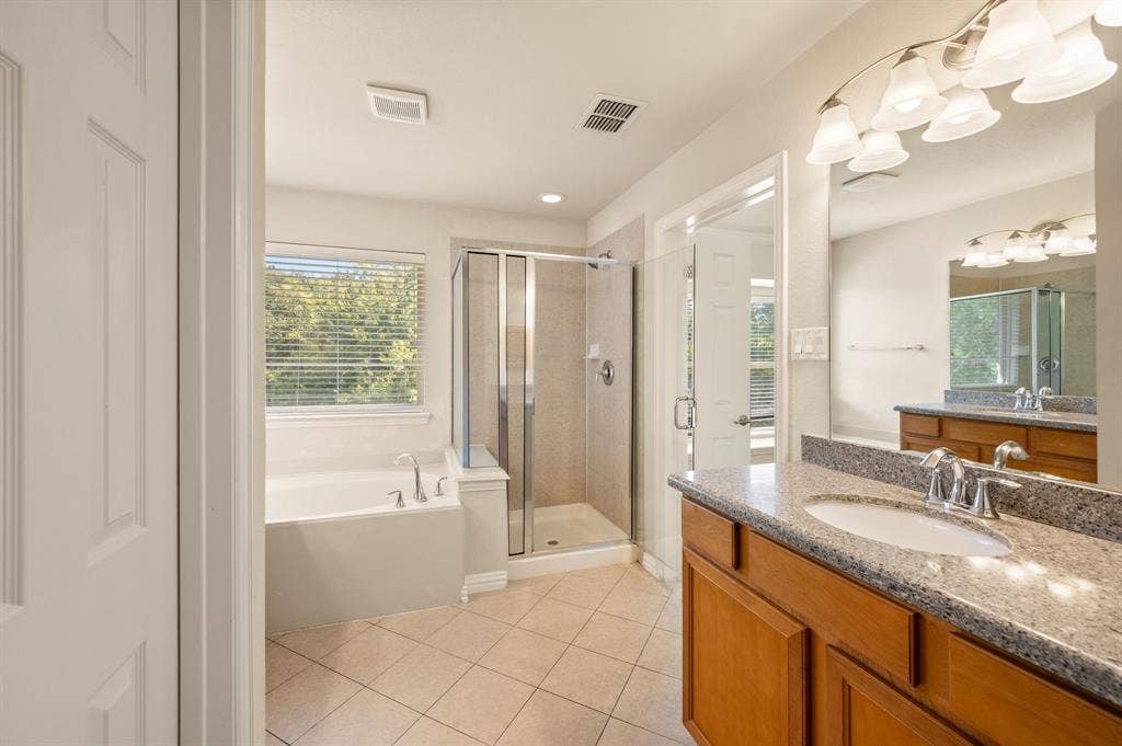 1712 Coronado Street, Allen, TX 75013 Bathroom featuring a vanity with stone-finish countertop, undermount sink, tiled walk-in shower with glass enclosure, deep soaking tub, and tile flooring