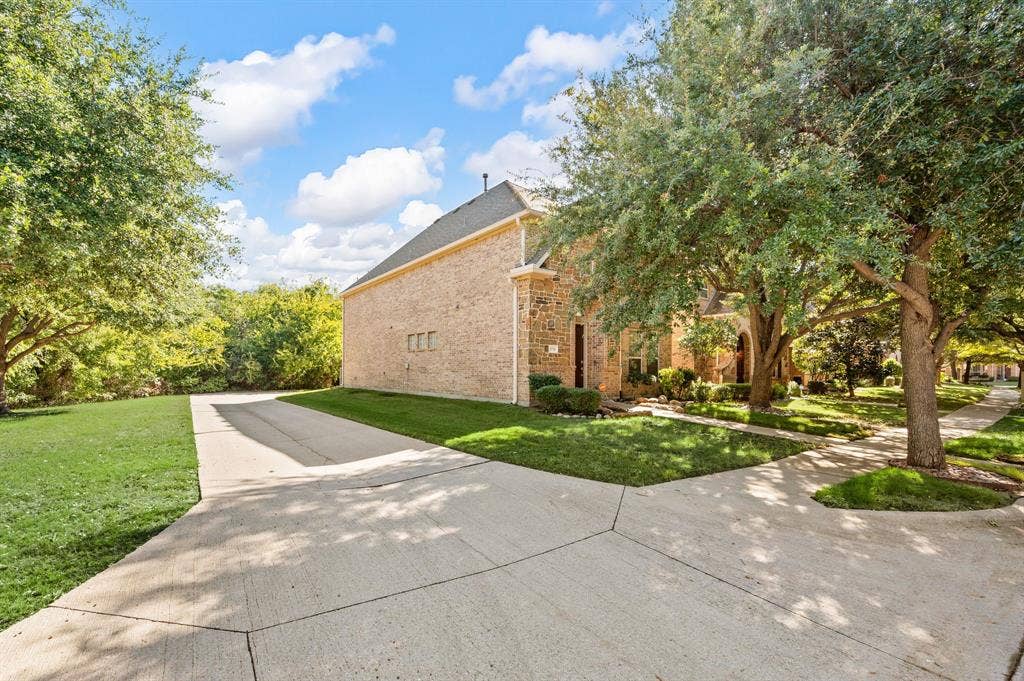 1712 Coronado Street, Allen, TX 75013 Brick exterior featuring a concrete driveway and mature trees on a landscaped lot
