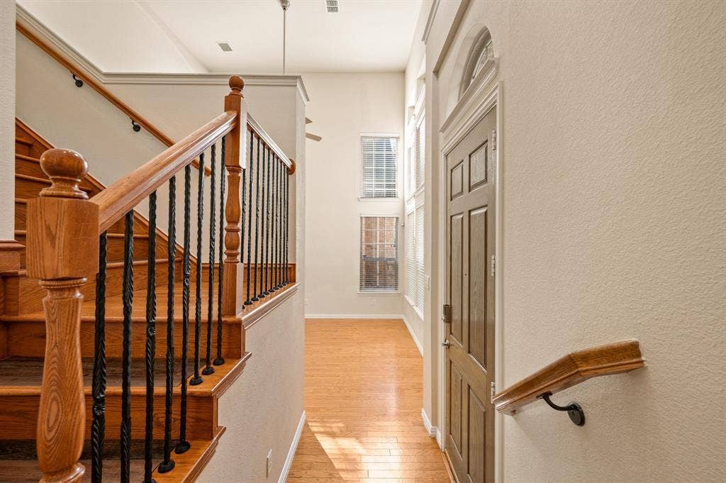 1712 Coronado Street, Allen, TX 75013 Entryway featuring high ceilings, wood-finish flooring, staircase with wood handrails and metal balusters, and multi-pane windows with arched transom detail