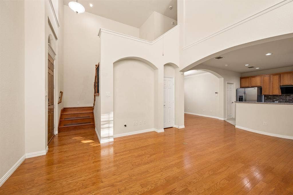 1712 Coronado Street, Allen, TX 75013 High-ceiling interior featuring wood-finish flooring, architectural arched wall niches, recessed lighting, and a breakfast bar