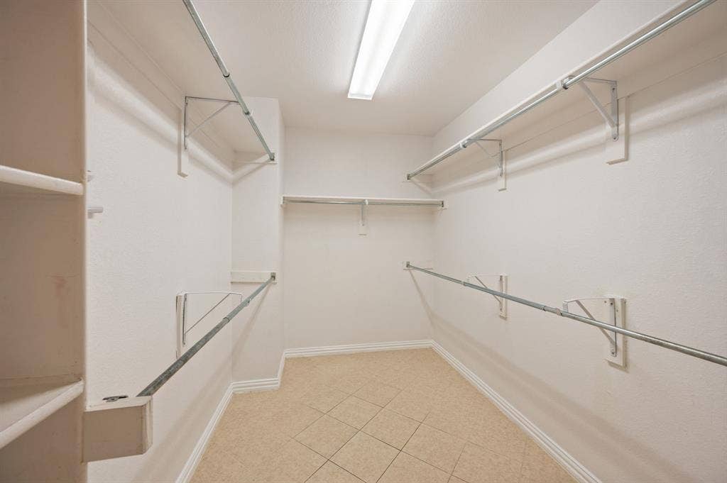 1712 Coronado Street, Allen, TX 75013 Walk-in closet featuring multi-level metal hanging rods, integrated wall shelving, linear ceiling lighting, and tiled flooring