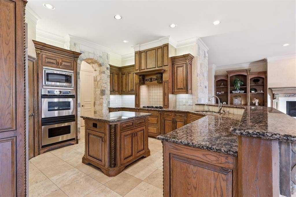 1919 Kings Pass, Heath, TX 75032 Kitchen featuring custom wood cabinetry, stone countertops, stainless steel appliances, a center island, and tile flooring